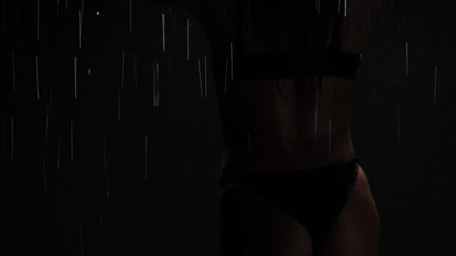 Blurred video silhouette of a girl in the shower washing her head on a black background.