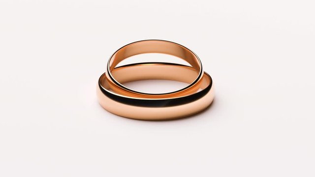 Wedding Golden Rings lie on white rotating background surface viewed from all sides with light copy space - Seamless Full HD loop footage
