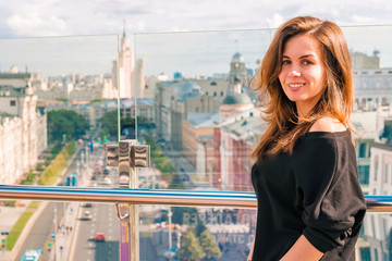 A young woman smiling on the roof with a panorama of Moscow