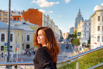 Fototapeta na wymiar Moscow / Russia - 15 Aug 2020: Portrait of a charming girl with the background of Moscow streets with high-rises and shops