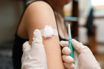 Girl with plaster on the shoulder from injection.
