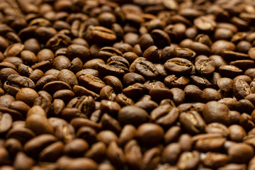 Scattered roasted coffee beans close-up with blurred foreground and background.