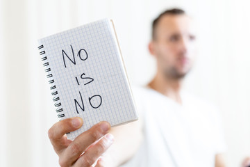 a man shows a sheet of paper with the inscription NO IS NO