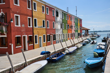  Street view with small boats on sea canal. Burano island in Venice.