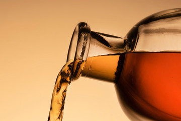 a bottle of whiskey, Bourbon, or liqueur. pouring liquid, a stream from the neck. close - up orange background