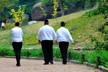 3 men, Hasidic Jews walk in the park in Uman. Ukraine, Jewish New Year, religious Jew.