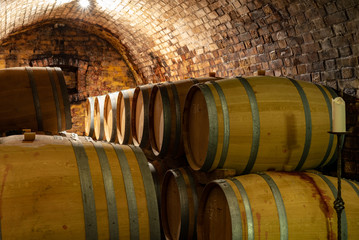 wooden old barrels in the rustic wine cellar with brick walls in villany hungary