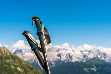 closeup of trekking poles with the dolomites in the background