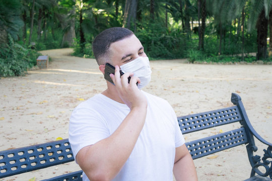 Closeup shot of a male holding a phone wearing a sanitary mask - concept of the new normal