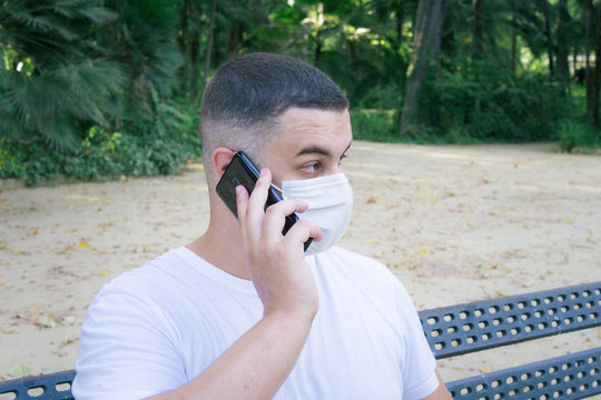 Closeup shot of a male holding a phone wearing a sanitary mask - concept of the new normal