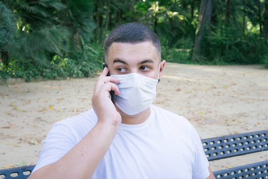 Closeup shot of a male holding a phone wearing a sanitary mask - concept of the new normal