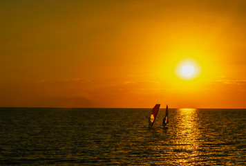 Fototapeta premium sunset at sea and two sail surfing sails on the horizon