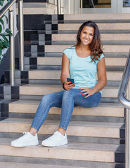 Young women with mobile phone sits on the steps