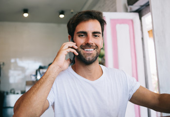 Half length portrait of cheerful bearded young male enjoying positive conversation on mobile phone,smiling young hipster guy 20s making smartphone call to banking operator satisfied with service