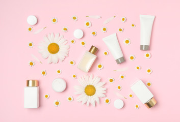 Flat lay composition with chamomiles and cosmetic products on pink background