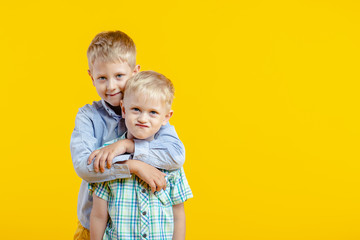 Brother hugging on camera on yellow background