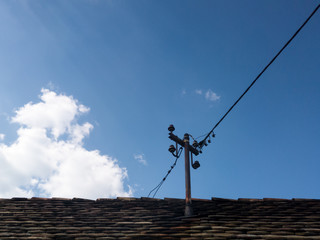 Rusty roof pole for electricity and power wires on the roof of an old house against the sky during...