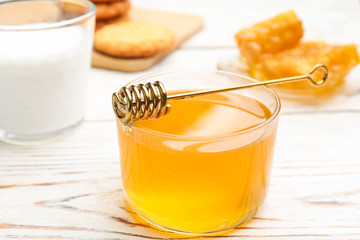 Tasty honey and metal dipper on white wooden table, closeup