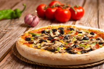 closeup of pizza with vegetables and pepperoni on wooden background