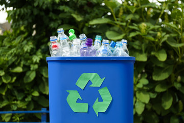 Many used bottles in trash bin outdoors, closeup. Plastic recycling