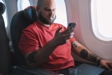 Serious man using smartphone while flight in plane