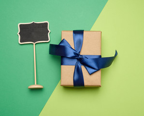 rectangular box wrapped in brown paper and tied with a silk blue ribbon with a bow