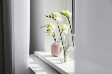 Beautiful white spring freesia flowers on window sill in room