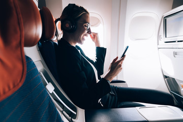 Happy female passenger dressed in formal wear feeling excited from received email with good news...