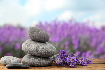 Naklejka na ściany i meble Spa stones and fresh lavender flowers on wooden table outdoors, closeup. Space for text