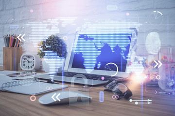 Double exposure of desktop with computer and world map hologram. International data network concept.