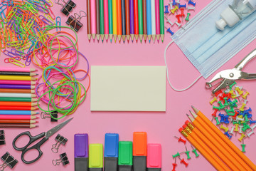 School stationery supplies with medical mask and hand sanitizer on pink background. Back to school...