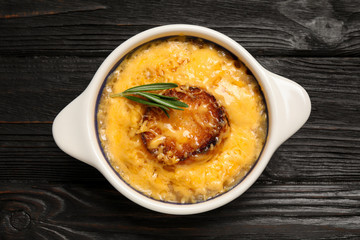 Tasty homemade french onion soup on black wooden table, top view