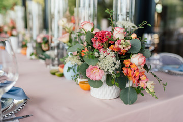 Floral wedding decoration. Wedding table setting decorated with fresh flowers. Wedding floristry. Bouquet with roses, eustoma and eucalyptus leaves.