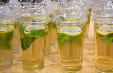 Lots of clear plastic cups with a lid and lemonade, or green tea with lemon and mint