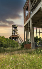 A disused coal mine pithead winding gear of an old Belgian coal mine shaft against a dramatic...