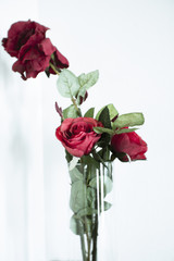Artificial red roses inside a glass vase decorating hotel room