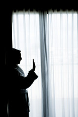 Silhouette of woman with bathrobe in front of a window