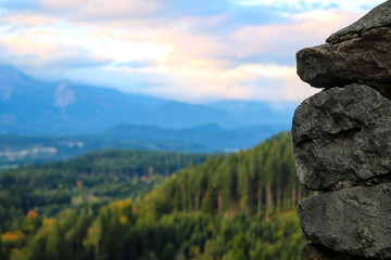 Close-up view of a part of a stone wall. Mountains and green forest.