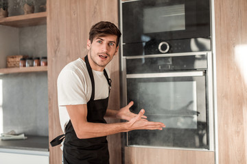 emotional young man standing near broken oven