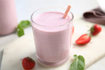 Tasty milk shake with strawberries and mint on white marble board