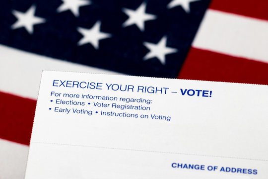 Closeup of voter registration identification card with American flag in background. Concept of right to vote, voter suppression and election