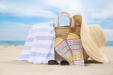 Different stylish beach objects on sand near sea