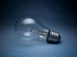 Electric light bulb on a blue textile background in the dark