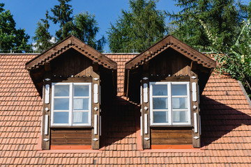 Fototapeta na wymiar Tiled roof attic. Cottage house rooftop window. Wooden village countryside architecture.