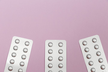 Pills in blister packs on a pink background