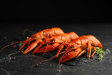Delicious boiled crayfishes with dill and pepper on black table