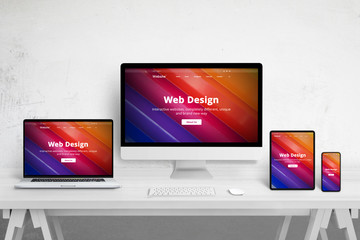 Responsive web site design on different devices. Web design studio desk with laptop, computer display, tablet and mobile phone