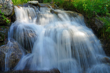 View of a running waterfall over boulders in the Laurance S. Rockefeller Preserve, a nature refuge on Phelps Lake in Grand Teton National Park in Jackson, Wyoming, United States