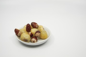 Matoa fruits and dried seed on small flat bowl with a white background