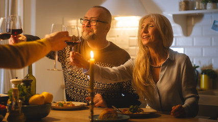 Happy Family Celebrating together, Sitting at the Table Eating Delicious Dinner Meal. Young Husband, Wife, Grandfather and Grandmother, Telling Stories, Joking, Raising Glasses to Toast